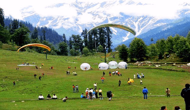 Paraglider soaring above Dalhousie hills with mountain views